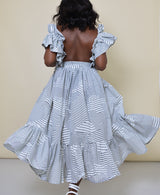 Model wearing The Kemist Barletta Backless Dress in White on a plain cream backdrop. 