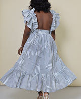 Model wearing The Kemist Barletta Backless Dress in White on a plain cream backdrop. 