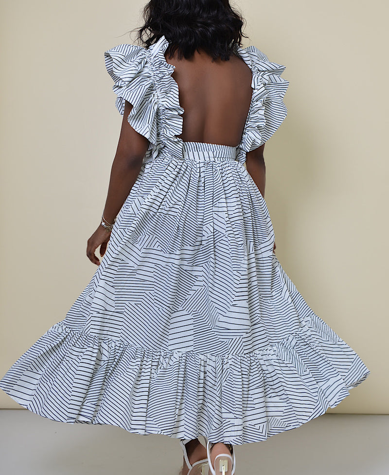 Model wearing The Kemist Barletta Backless Dress in White on a plain cream backdrop. 