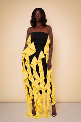 Model wearing The Kemist Seville Strapless Waterfall Ruffle Dress in Black and Yellow on a plain cream backdrop.